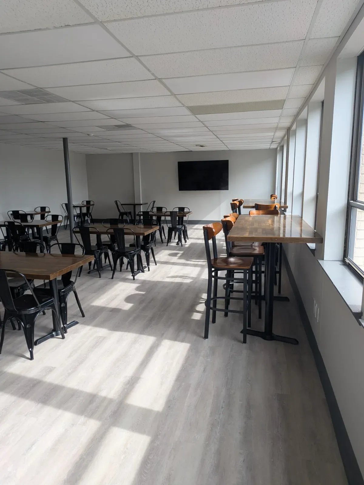 Café-style tables and chairs on a sunlit floor in the MC² workspace